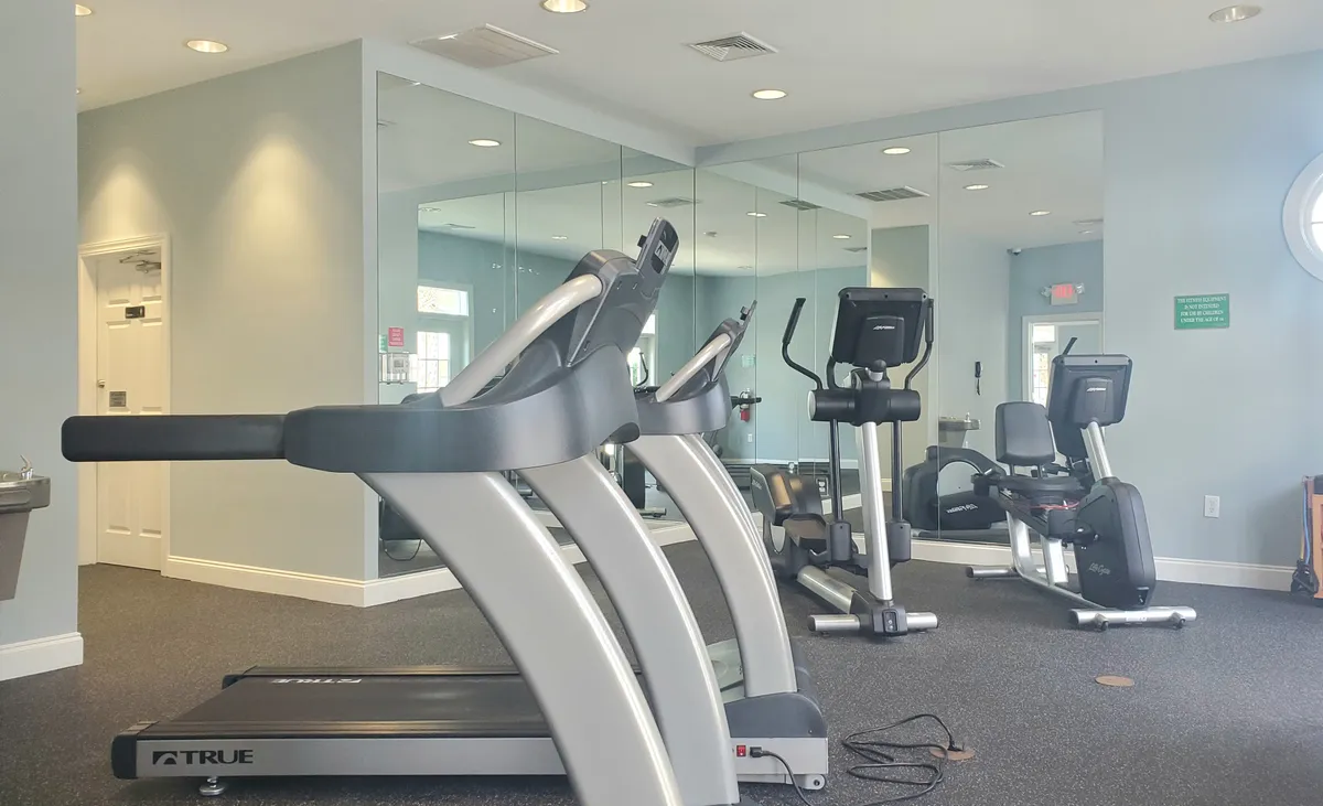 A bright, modern fitness center filled with treadmills, an elliptical machine, an exercise bike, and mirrored walls. The room exudes energy, offering a spacious, well-equipped environment for guests to engage in solo or group workouts.