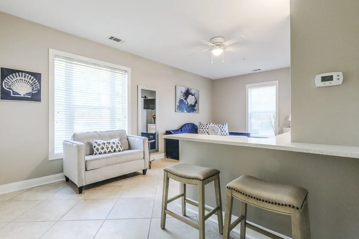 A cozy corner of the studio featuring a comfortable armchair, bar seating, and decorative wall art. Morning light fills the space, creating a relaxed ambiance ideal for reading, casual conversations, or enjoying coffee. Thoughtful décor accents contribute to the inviting sanctuary feel.
