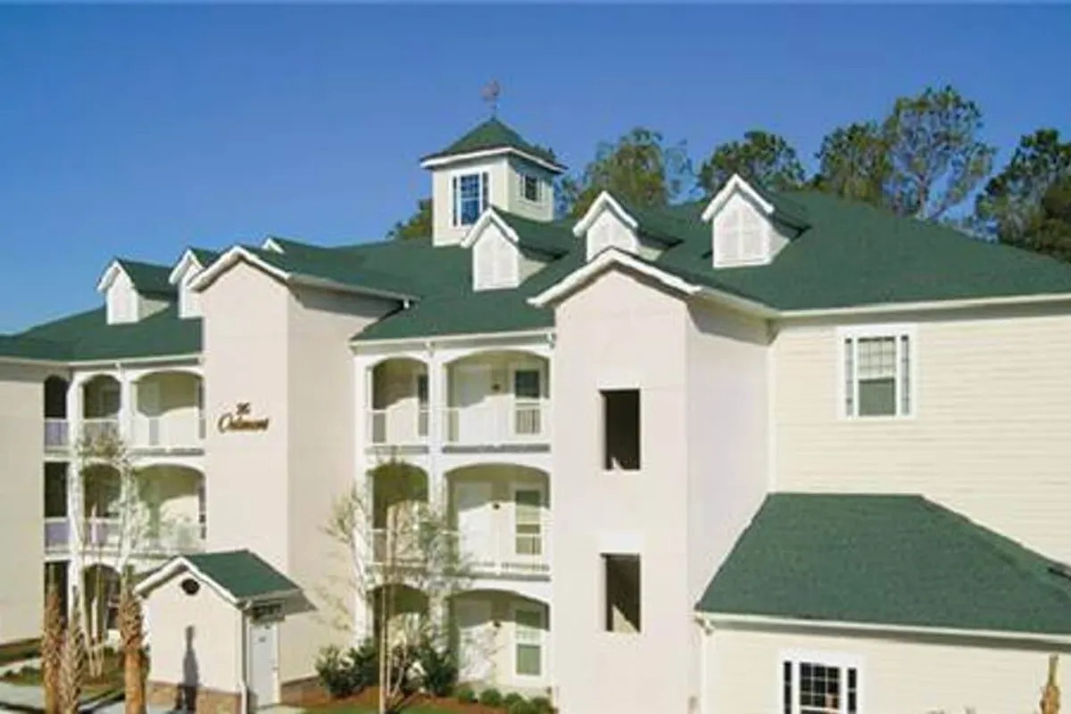 A wide exterior view featuring the resort’s distinctive cupola, green roof, and white facade, with balconies and landscaped surroundings. The scene conveys a welcoming, resort-like setting perfect for social or romantic exploration.